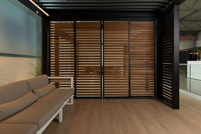 Innenansicht einer modernen Lamellen-Schiebewand mit Holzoptik und Sofa