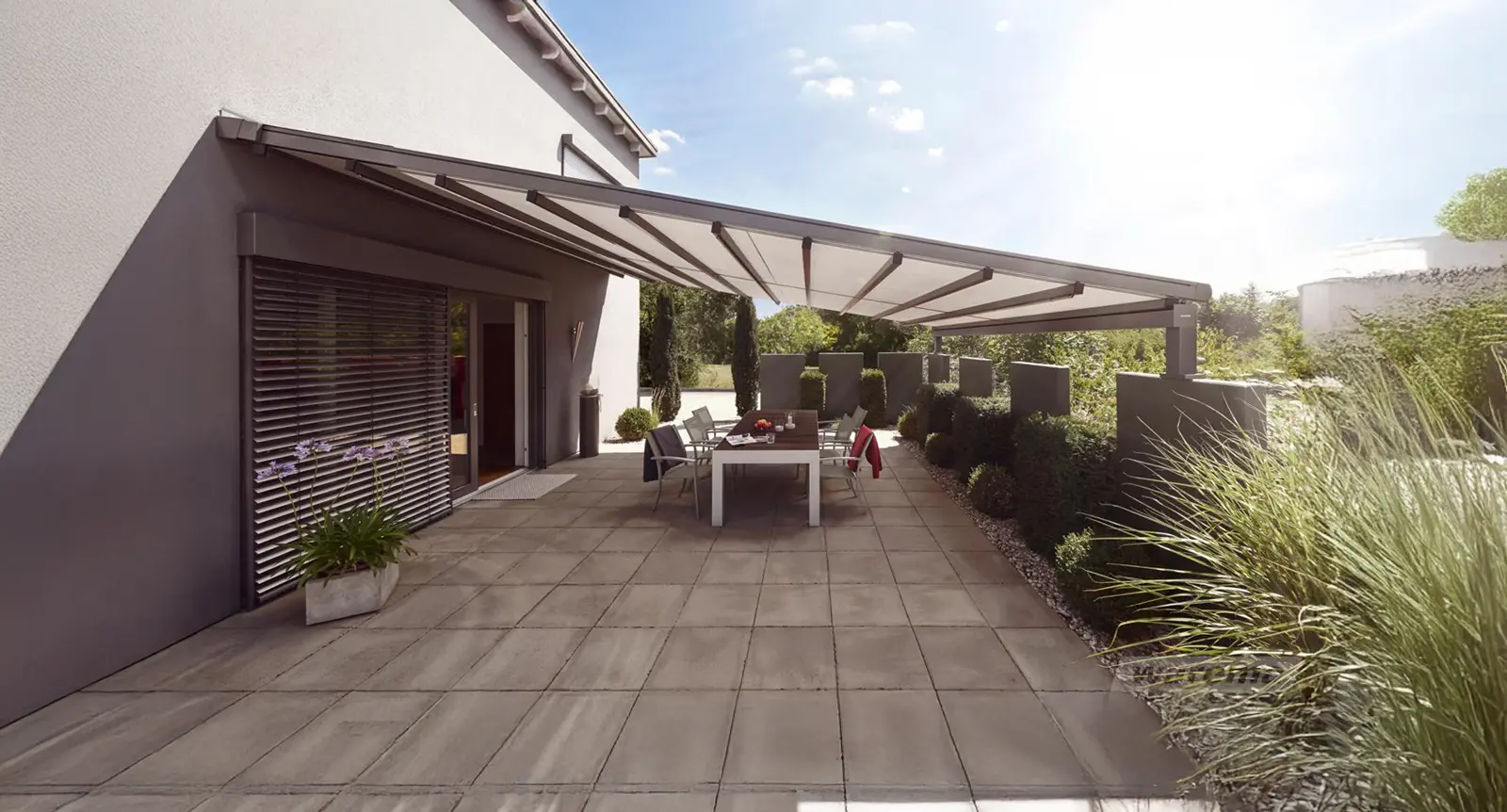 Pergolamarkisen als großflächiger Sonnen- und Wetterschutz über einer modernen Terrasse